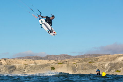 Duotone Pro Voke 2020 kite surfboard during kitesurfing at an ocean coastline with rocky desert cliffs