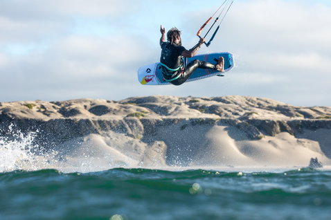 Duotone Pro Voke directional kiteboard during kitesurfing at ocean beach with sandy dunes