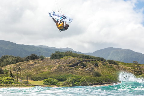 Duotone Pro Voke kite surfboard during kitesurfing at a tropical coastal beach with green hills and ocean
