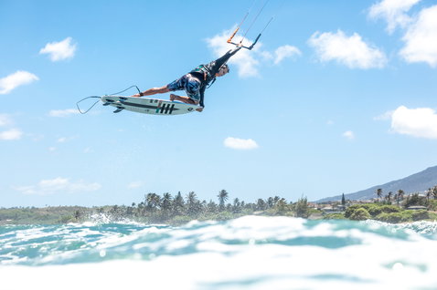 Duotone Pro Wam kiteboard de vagues lors de kitesurf sur un littoral tropical avec palmiers et montagnes