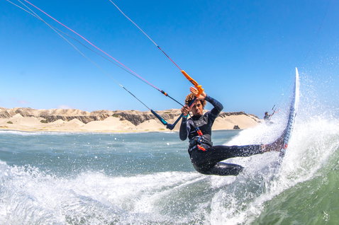 Duotone Pro Wam kiteboard de vagues lors du kitesurf sur une plage océanique avec dunes