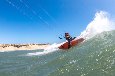 Duotone Wam 2021 wave kiteboard during wave riding at the ocean beach with sandy dunes