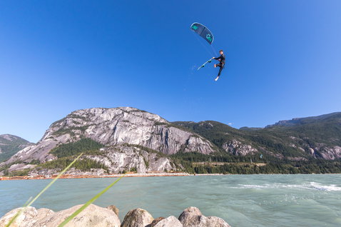 Duotone Evo 2021 LEI Kite beim Kitesurfen an einem Bergsee mit felsigem Ufer und bewaldeten Bergen