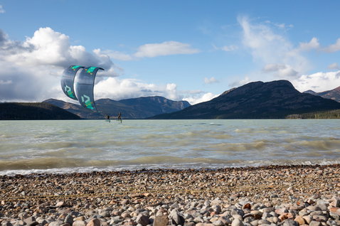 Duotone Evo LEI Kite beim Kitesurfen an einem Alpensee mit Bergpanorama und Kieselstrand