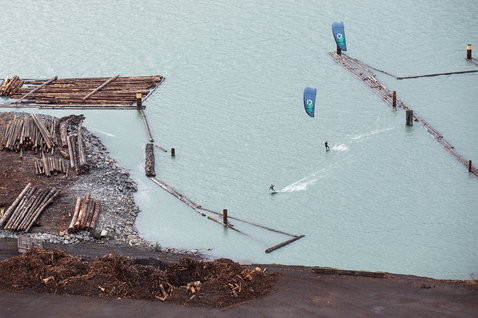 Duotone Evo LEI Kite beim Kitesurfen an einem Industriewasserweg mit Holzlager