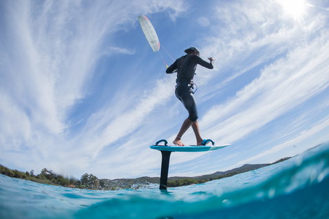 Duotone Daytona 105 foil board durante foiling en el océano en una bahía costera con colinas
