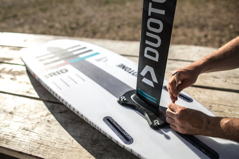 Duotone Hybrid tabla de kitesurf en blanco, gris oscuro y verde azulado durante el montaje del foil