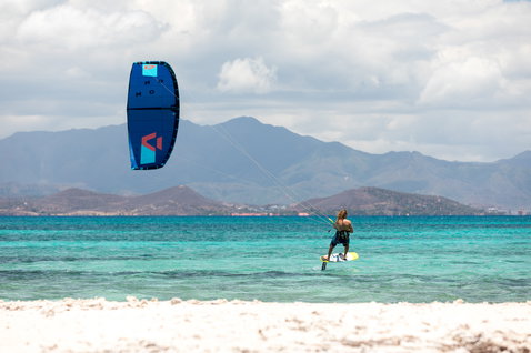 Cometa LEI Duotone Mono 2020 durante el kitesurf en una playa tropical con océano turquesa y montañas