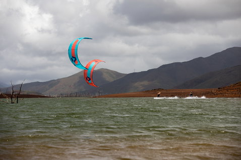 Duotone Juice LEI Kite beim Kitesurfen an einem Binnensee mit karger Bergkulisse