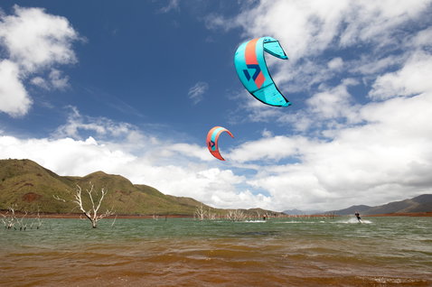 Duotone Juice 2020 LEI Kite beim Kitesurfen an einer Binnenlagune mit kahlen Bäumen und Bergkulisse