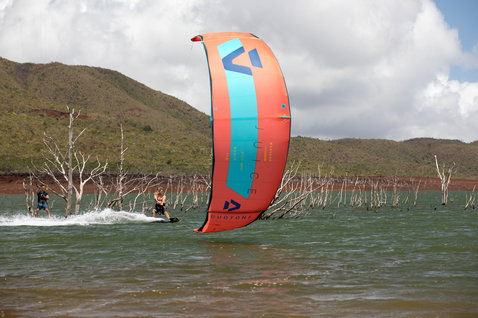 Duotone Juice LEI Kite beim Kitesurfen in einer Binnenlagunemit abgestorbenen Bäumen und Hügeln im Hintergrund