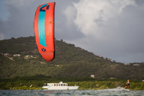 Duotone Juice LEI Kite beim Kitesurfen in einer tropischen Küstenlagune mit grünem Hang und Boot