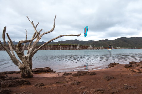 Duotone Kiteboarding Pace 2021 Foil-Kiteboard beim Foilen auf einem Binnensee mit roter Erdküste