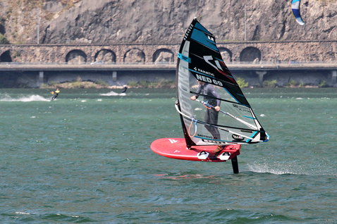 Duotone WARP_FOIL foil sail while foiling in a river gorge with rocky cliff and bridge arches