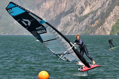 Duotone WARP_FOIL foil sail 8.8m² while foiling on an alpine lake with mountain backdrop