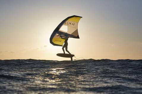 Ala foil Duotone Unit durante wing foiling sull'oceano nella luce del tramonto dorato