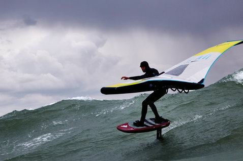 Duotone Unit foil wing durante wing foiling su onde oceaniche con cielo nuvoloso