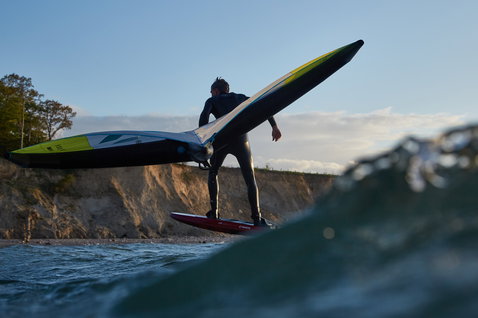 Duotone Unit foil wing durante il wing foiling in costa in grigio scuro e verde lime