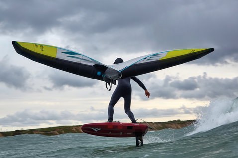 Duotone Unit foil wing durante il wing foiling sull'oceano con tavola da foil Fanatic sotto cielo nuvoloso