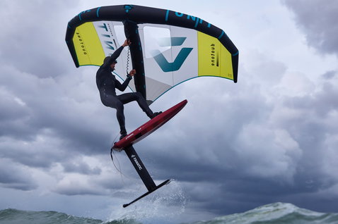 Duotone Unit foil wing durante il wing foiling sopra l'oceano con cielo nuvoloso e drammatico