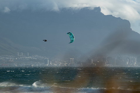 Duotone Dice LEI kite durante il kitesurf in una baia con paesaggio urbano e montagne