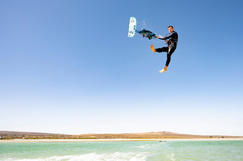 Duotone Dice kite LEI durante il kitesurf in una laguna turchese lungo la costa arida