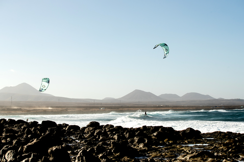 Duotone Kiteboarding Neo SLS LEI Kite beim Wellenreiten am Ozean mit felsiger Küste