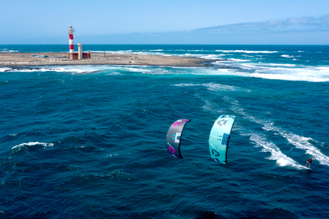 Duotone Neo SLS LEI Kite beim Wellenreiten am Ozean mit Leuchtturm-Küste