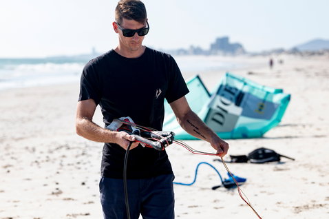 Duotone Click Bar Quad Control 2022 Steuerbar beim Ausrüsten am Sandstrand mit Küstenstadt im Hintergrund