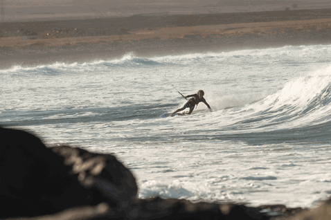 Duotone Session SLS tabla de kitesurf durante el kitesurf en una playa oceánica rocosa