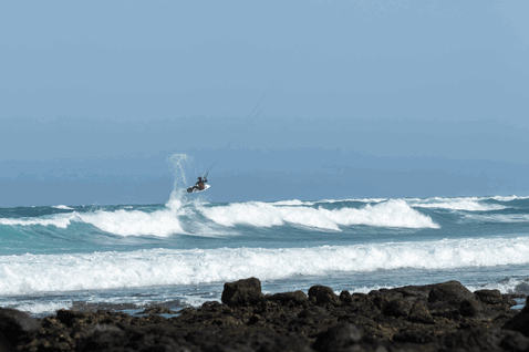 Duotone Wam SLS Kite-Surfboard beim Kitesurfen am Ozean mit vulkanischer Felsküste