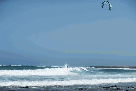 Duotone Wam SLS Kiteboard beim Wellenreiten am Meer mit Felsenküste