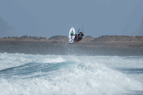 Duotone Wam SLS Kite-Surfboard beim Kitesurfen an einer felsigen Ozeanküste