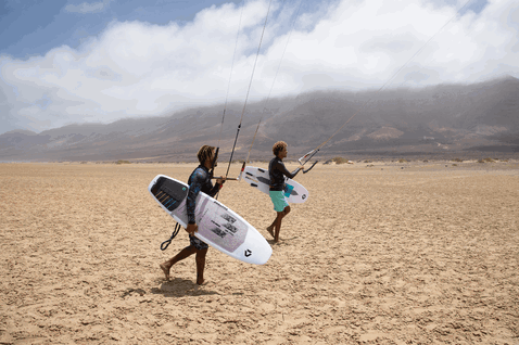 Duotone Hybrid SLS surfboard durante il kitesurf su una spiaggia desertica con montagne sullo sfondo