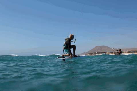 Duotone Hybrid SLS kite surfboard durante il kitesurf sull'oceano con montagne vulcaniche sullo sfondo