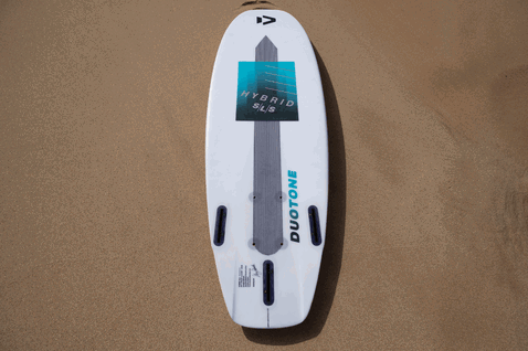Duotone Hybrid SLS kite surfboard in bianco, teal e blu chiaro su spiaggia sabbiosa