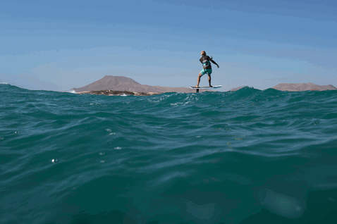 Duotone Hybrid SLS tavola da kitesurf durante il surf sulle onde su una costa di isola vulcanica