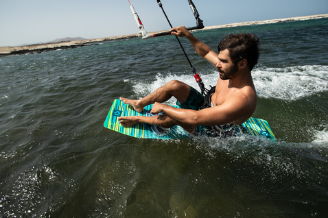 Duotone Spike twin-tip kiteboard durante il kitesurf in una baia oceanica dalle acque piatte