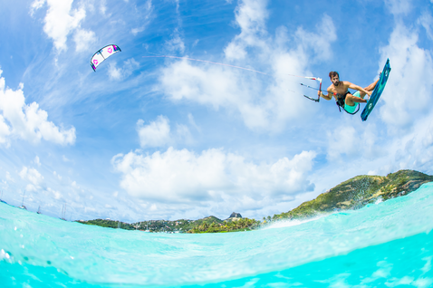 Duotone Evo SLS LEI kite durante el kitesurf en el océano tropical con isla exuberante al fondo