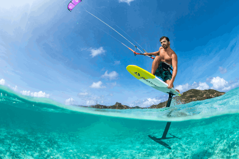 Duotone Mono LEI kite during foiling on a tropical ocean with clear turquoise water and island in the background