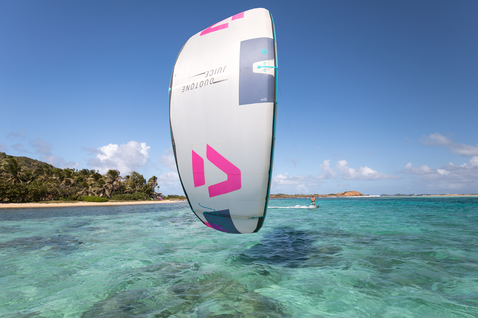 Duotone Juice LEI Kite beim Kitesurfen in einer tropischen Ozeanlagune mit Sandstrand und Palmen im Hintergrund