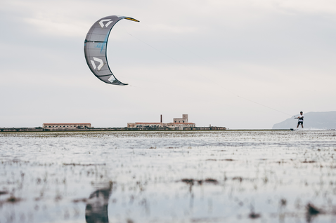 Duotone Juice D/LAB LEI Kite beim Kitesurfen in einer Küstenlagune mit historischem Gebäude im Hintergrund