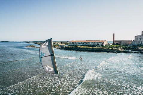 Duotone Juice D/LAB LEI Kite beim Kitesurfen an einer Küstenförde mit historischen Steingebäuden