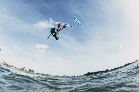 Kite LEI Duotone Vegas durante il kitesurf in oceano con palme e riva