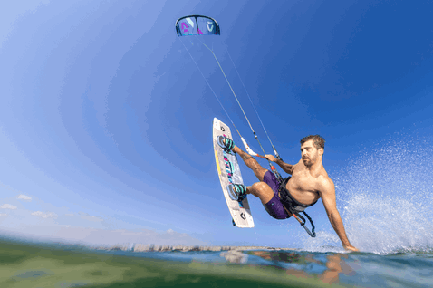 Duotone Dice SLS LEI kite during kitesurfing at an ocean beach in cobalt blue and white