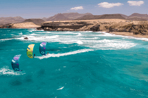 Duotone Dice SLS LEI kite during kitesurfing at ocean beach with rocky coastline