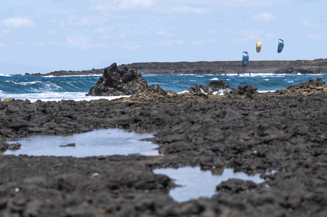 Duotone Dice SLS LEI kite during kitesurfing at a volcanic rocky coastline with ocean