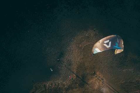 Duotone Gonzales tabla de kitesurf twin-tip durante kitesurf en playa con terreno rocoso y arenoso