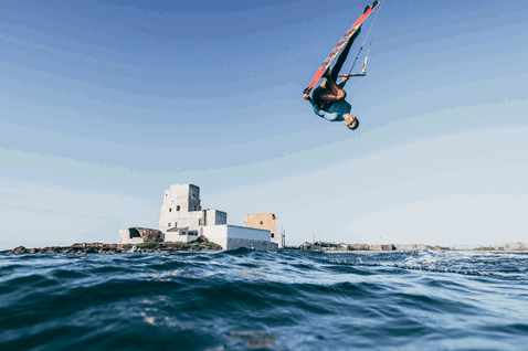 Duotone Gonzales tabla de kitesurf twin-tip durante kitesurf en océano abierto con fortaleza histórica en isla rocosa al fondo