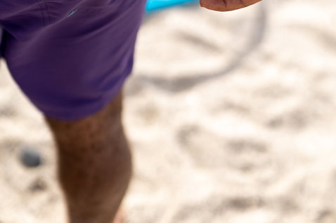 Boardshorts en prune en pose sur une plage au bord de l'océan